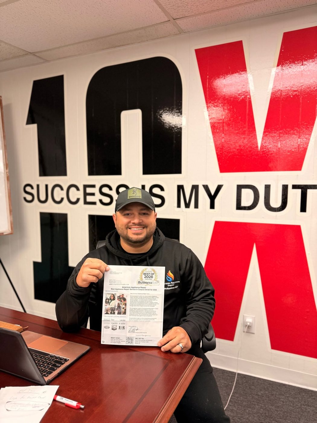 Rafael holding the BusinessRate Best of 2026 award for Best Appliance Repair Service in Corpus Christi, in front of the 'Success is my duty' wall