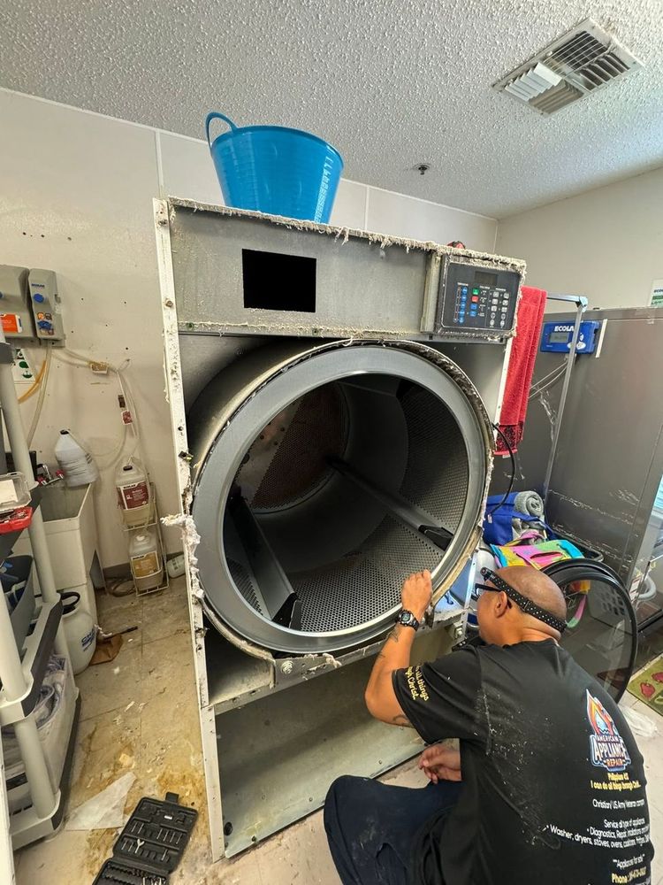 Commercial dryer service — one of our technicians deep inside a laundry-facility machine. Commercial equipment isn't a sideline here; it's a specialty.